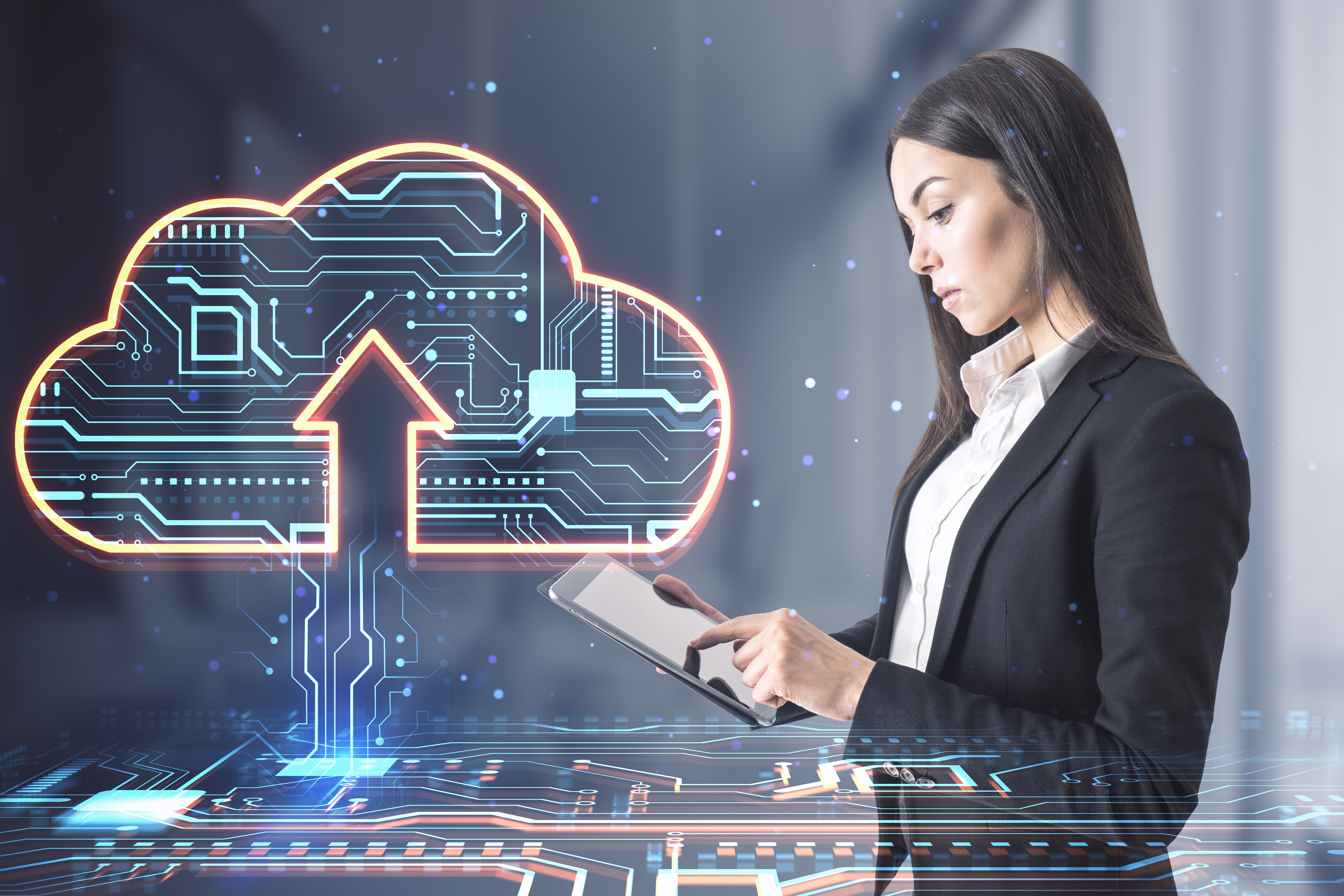 a woman in a buisness suit is using a tablet, a cloud with an up arrow is superimposed on the image. The cloud is filled with circuitry
